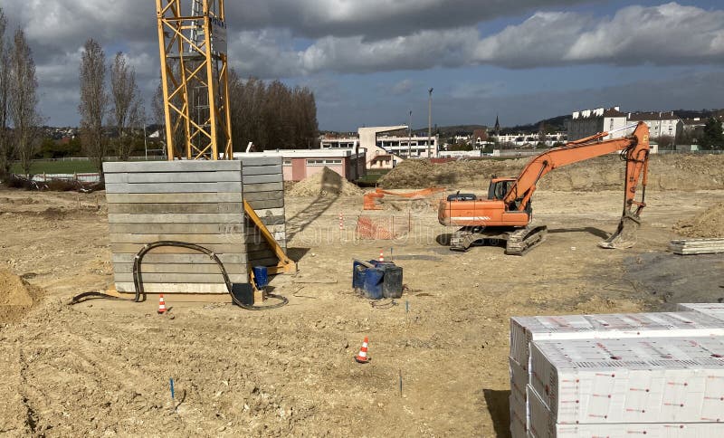 Construction site featuring a large, orange excavator on a dirt field stock images