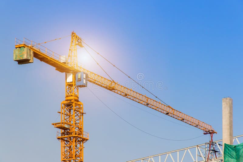 A construction site including several cranes working on a building, Boom crane on the construction of a high-rise and scaffolding