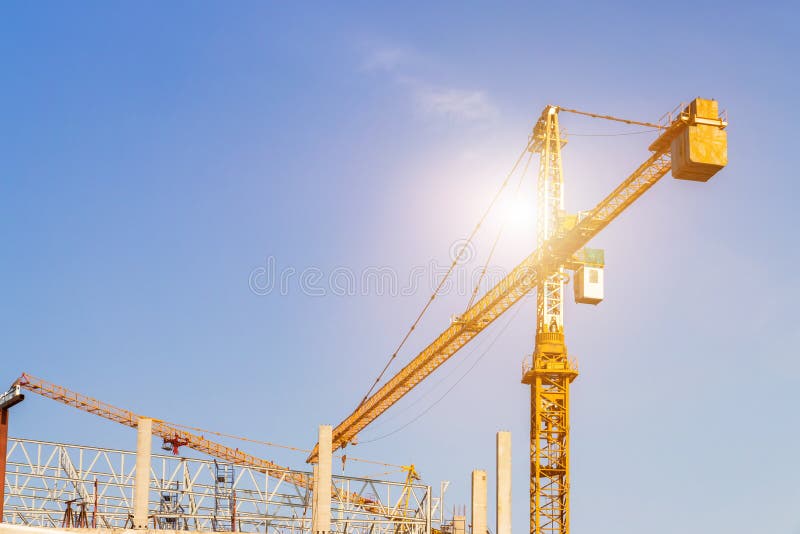 A construction site including several cranes working on a building, Boom crane on the construction of a high-rise and scaffolding