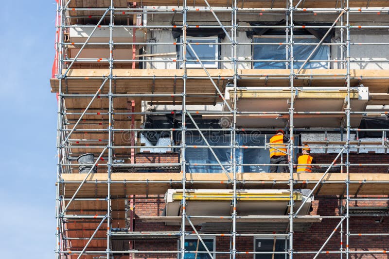 Construction site new apartment building with scaffolding and mason workers royalty free stock photo
