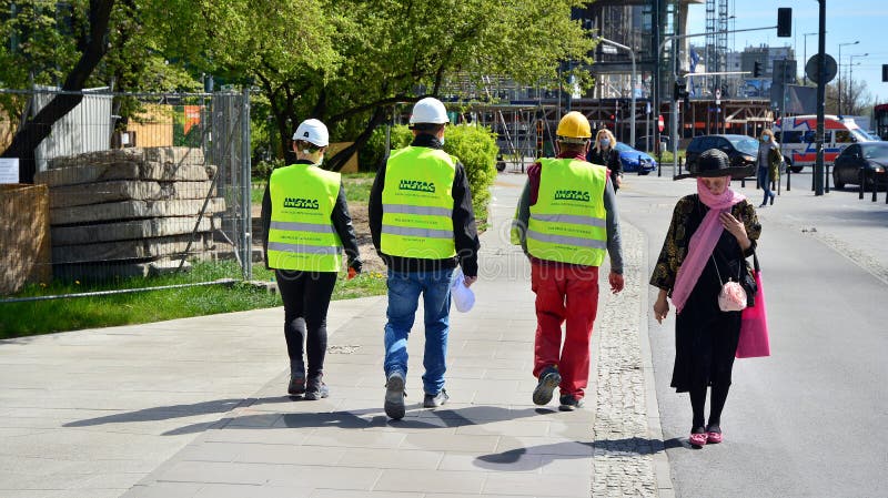 On the construction site is a new high-rise office building. Builders are walking down the street to work