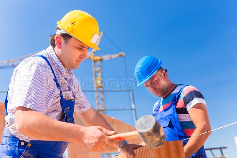 Construction site workers building walls on house