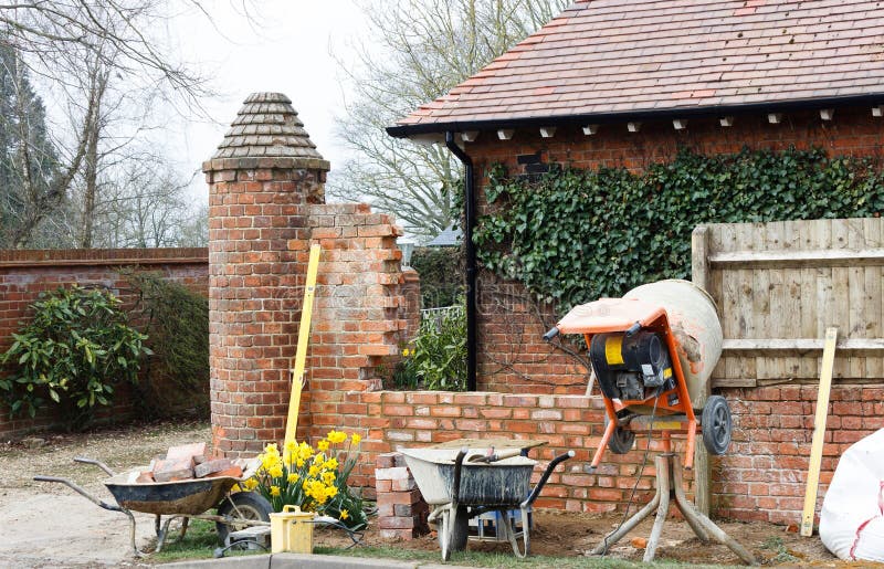 Construction work, brick laying, contructing garden wall, UK. Construction work with tools and cement mixer, building a brick garden wall outside a UK house royalty free stock photography Construction work, brick laying, contructing garden wall, UK. Construction work with tools and cement mixer, building a brick garden wall outside a UK house royalty free stock photography