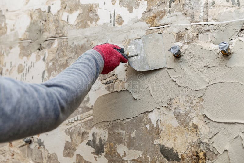 Construction worker applying plaster on the old bathroom wall royalty free stock image