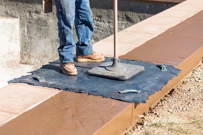 Construction Worker Applying Pressure to Texture Template On Wet Cement royalty free stock photography