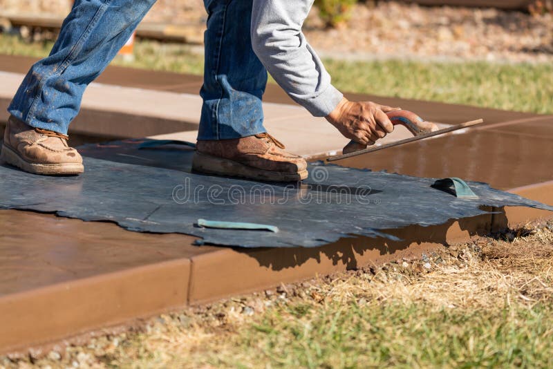 Construction Worker Applying Pressure to Texture Template On Wet Cement stock photography