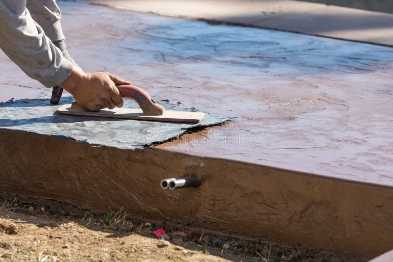 Construction Worker Applying Pressure to Texture Template On Wet Cement stock images