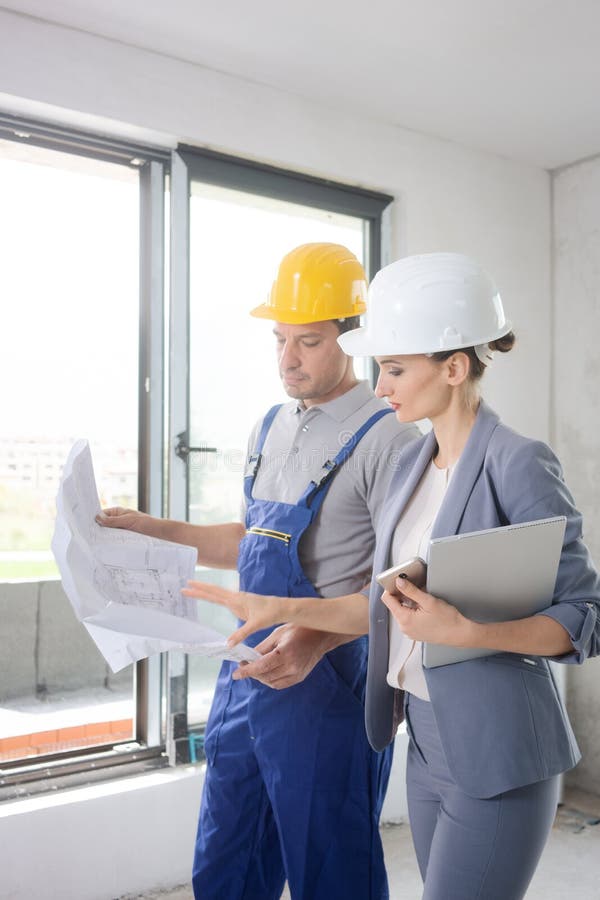 Construction worker and architect looking at plan on site royalty free stock photography