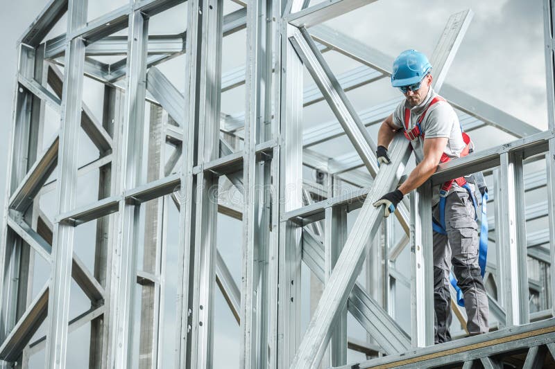 A construction worker is focused on assembling metal framework at a building site under clear skies. Safety gear is notably worn during this task. Load structural stock images, royalty-free photos and pictures