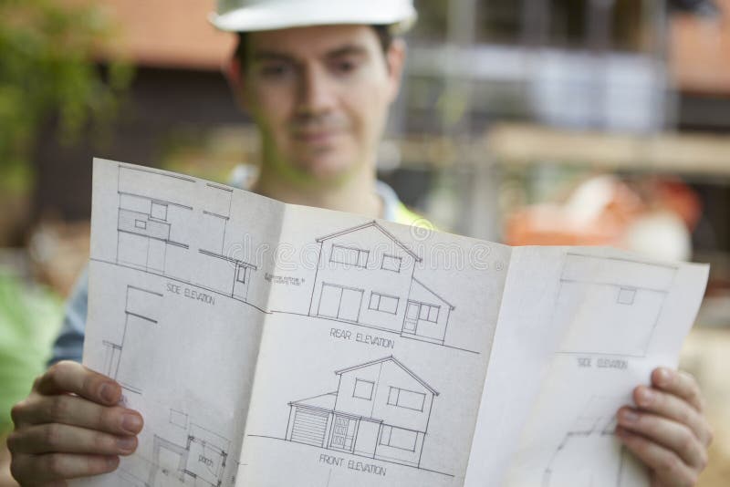 Male Construction Worker On Building Site Looking At House Plans