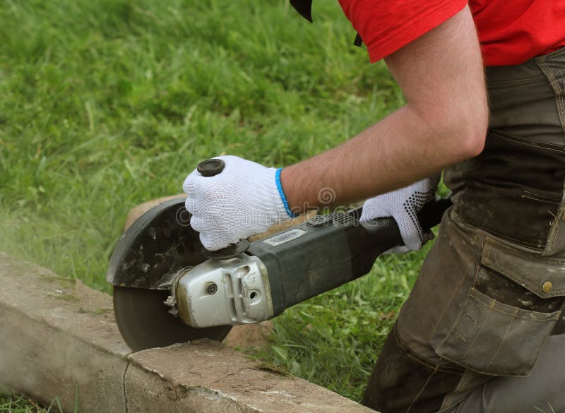 Construction Worker Cutting Concrete Plate for Fence Foundation Using a