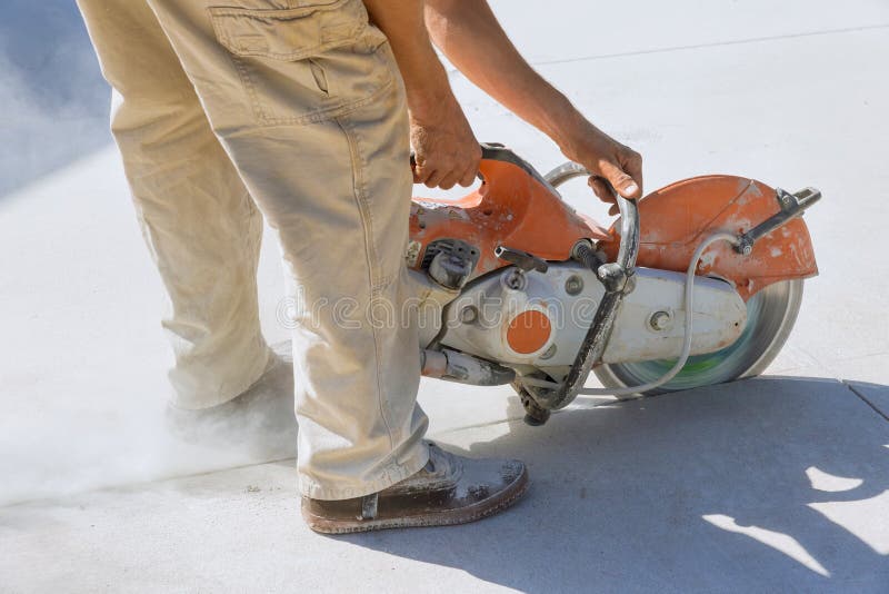 This is a Construction Worker Cutting Concrete Slabs for Sidewalks