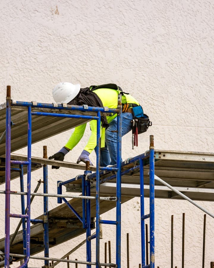 Construction Worker with Face Mask Installing Scaffolding for Building