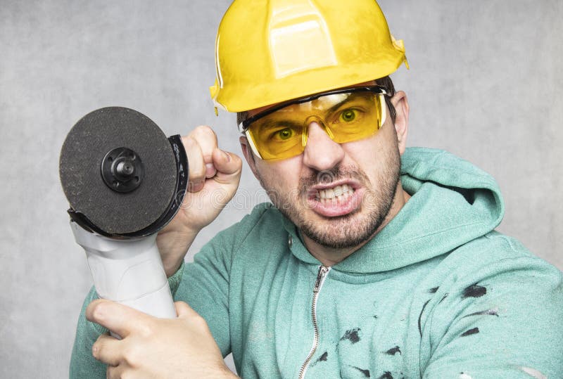 The Construction Worker Holds an Angle Grinder in His Hand Stock Photo