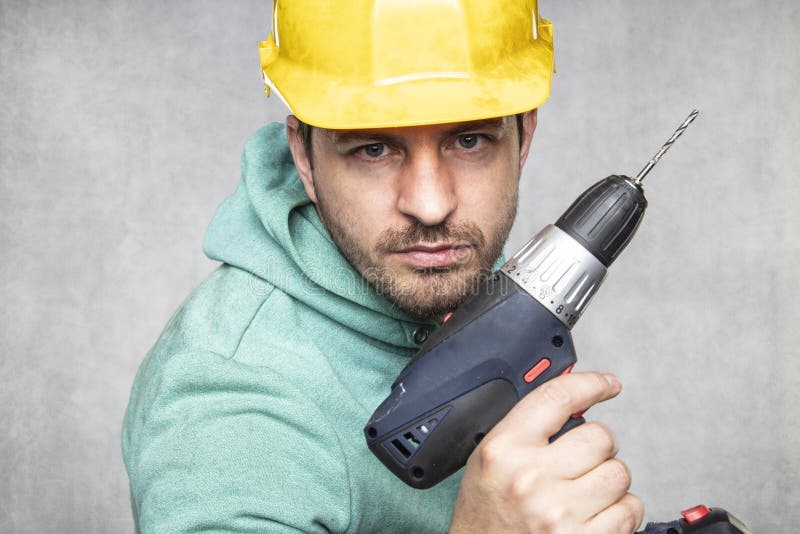 The construction worker holds an electric screwdriver in his hand, various situations royalty free stock image