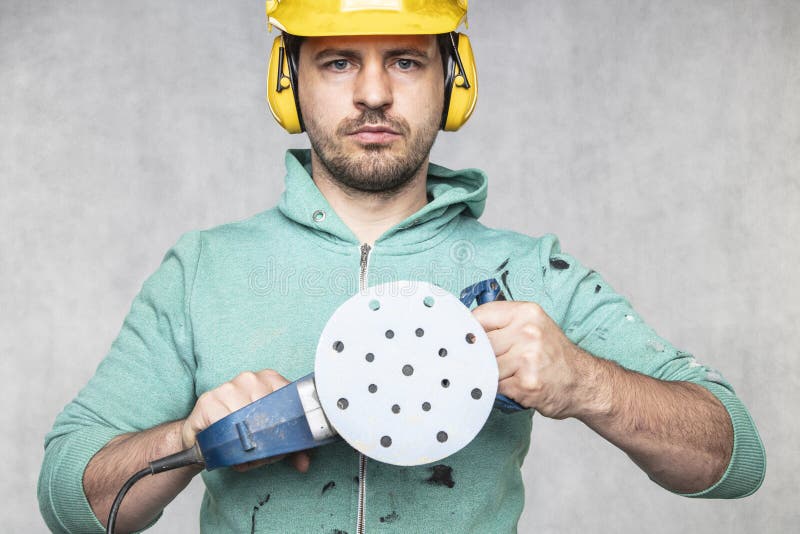 The construction worker holds a new grinder in his hand, close up, front view stock image