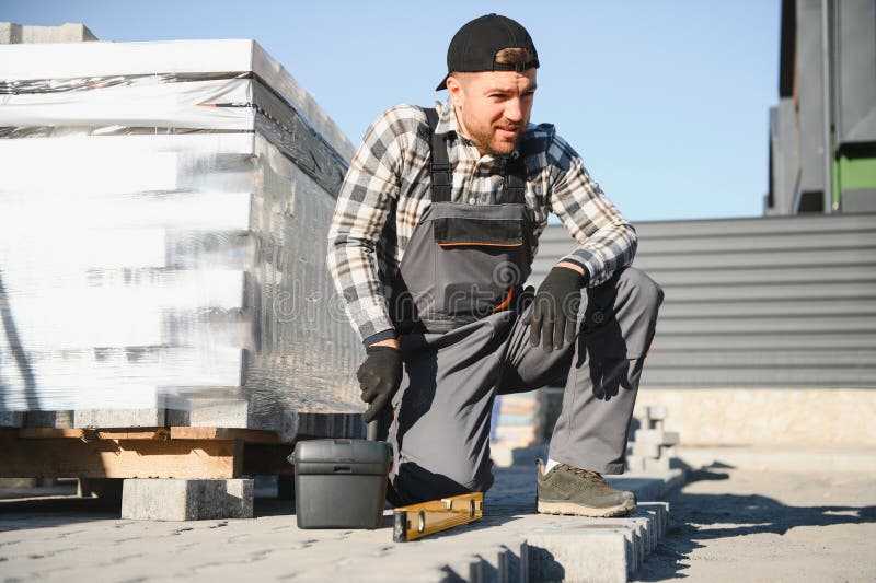Construction worker installing and laying pavement stones on terrace, road or sidewalk. Worker using stones and rubber stock photography