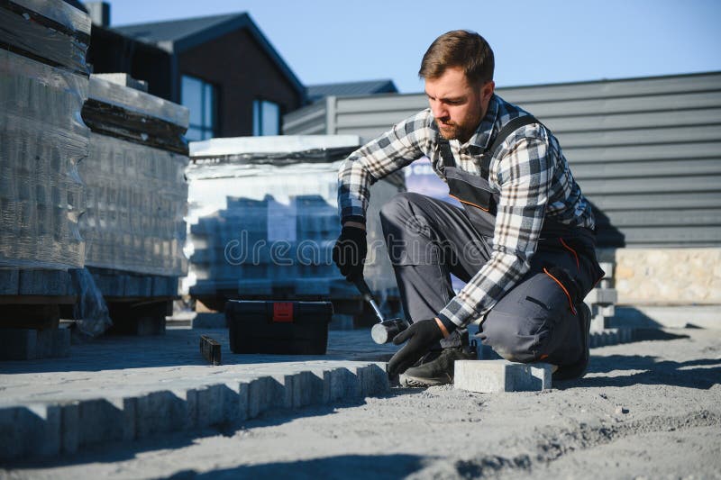 Construction worker installing and laying pavement stones on terrace, road or sidewalk. Worker using stones and rubber royalty free stock image