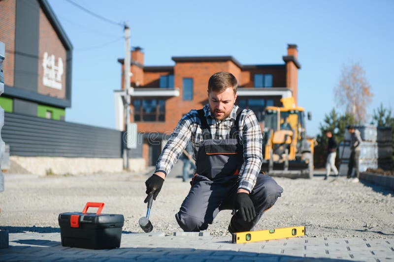 Construction worker installing and laying pavement stones on terrace, road or sidewalk. Worker using stones and rubber stock photography