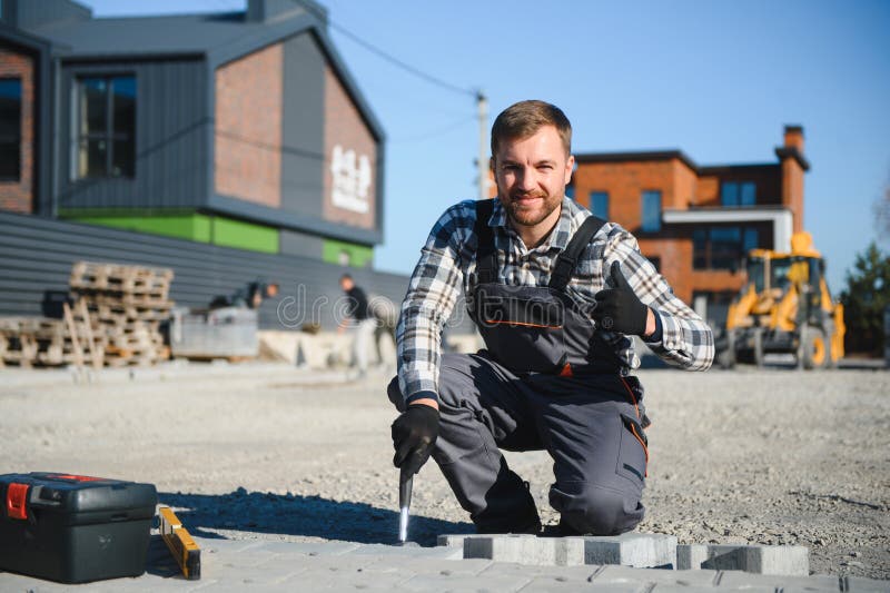 Construction worker installing and laying pavement stones on terrace, road or sidewalk. Worker using stones and rubber stock photo