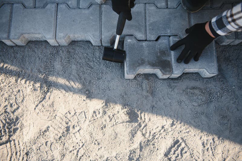 Construction worker installing and laying pavement stones on terrace, road or sidewalk. Worker using stones and rubber stock photo