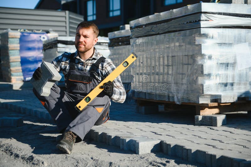 Construction worker installing and laying pavement stones on terrace, road or sidewalk. Worker using stones and rubber stock photos