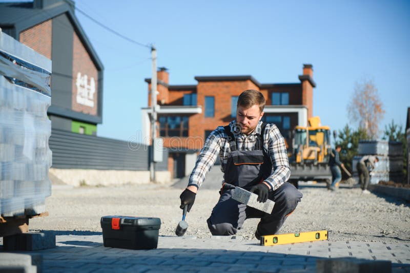 Construction worker installing and laying pavement stones on terrace, road or sidewalk. Worker using stones and rubber stock photos