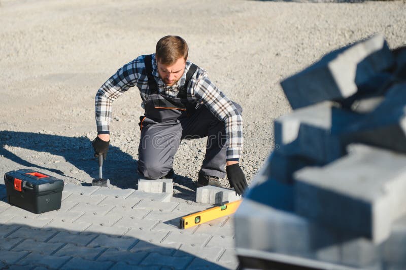 Construction worker installing and laying pavement stones on terrace, road or sidewalk. Worker using stones and rubber royalty free stock photos