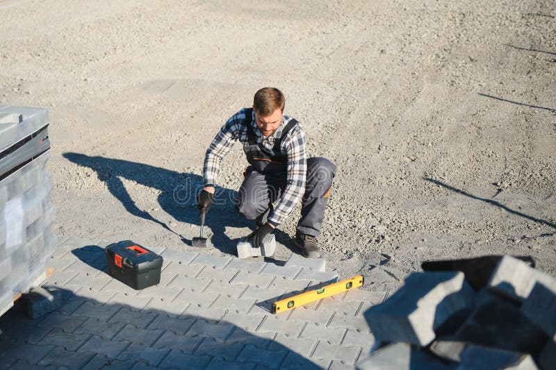 Construction worker installing and laying pavement stones on terrace, road or sidewalk. Worker using stones and rubber stock images
