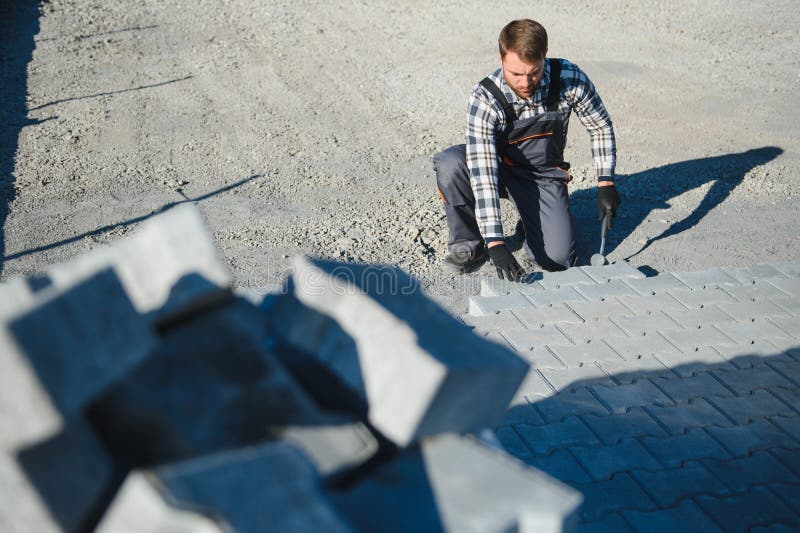 Construction worker installing and laying pavement stones on terrace, road or sidewalk. Worker using stones and rubber royalty free stock images