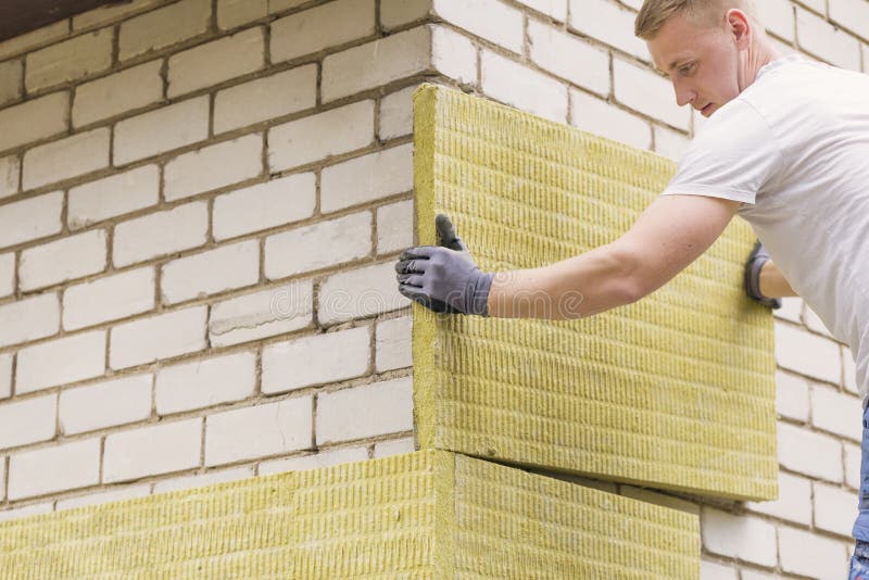 Construction worker insulating house facade with mineral wo