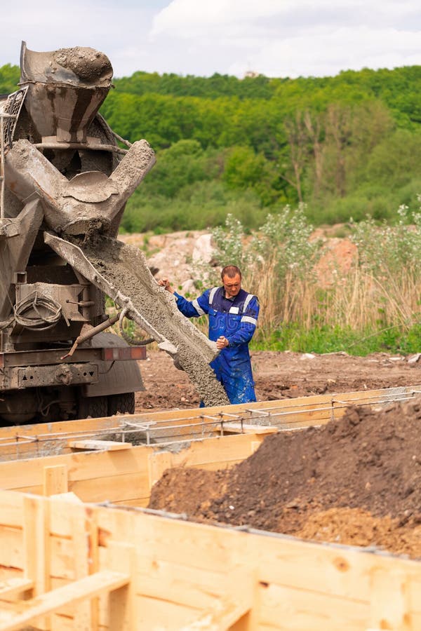 Construction Worker Laying Cement or Concrete into the Foundation