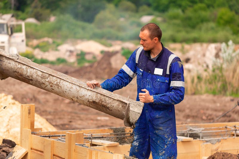 Construction Worker Laying Cement or Concrete into the Foundation