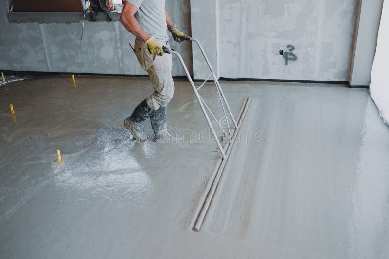 Construction worker leveling concrete surface flooring using bull float stock photos