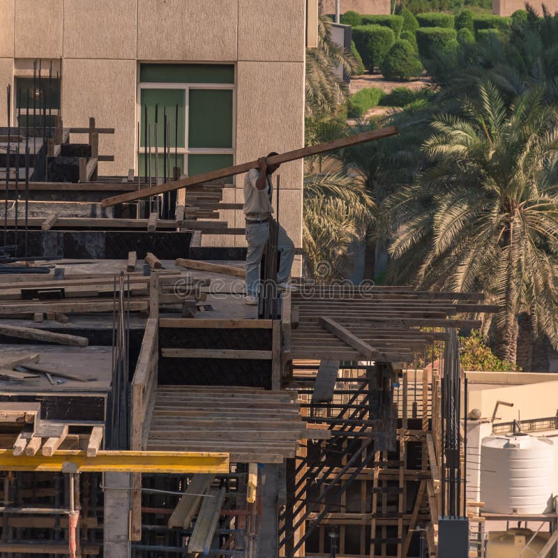 Construction Worker Bent Lifting Heavy Load on Building Site Stock