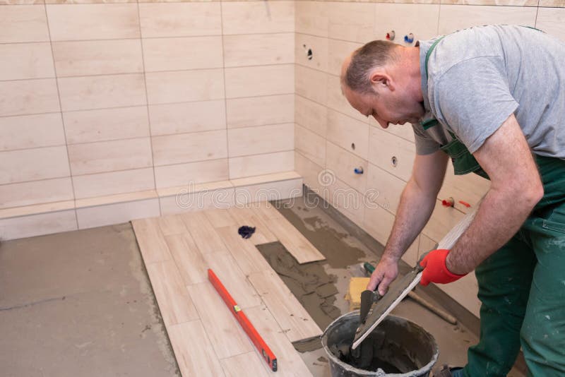 Free Photo  Builder checks the quality of the laid tiles with a manual  bubble level construction worker installing ceramic floor tiles on  construction sites floor repair selective focus