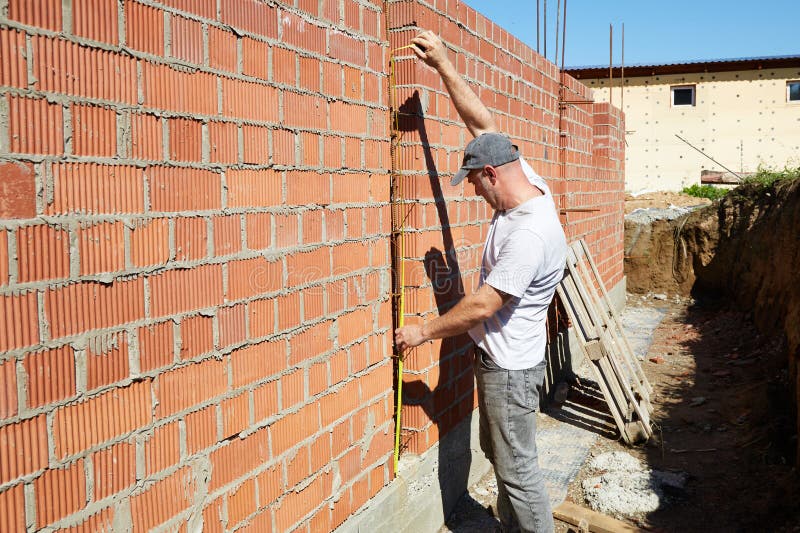 A construction worker is measuring a brick wall at a building site stock photos
