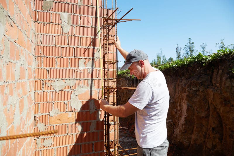 A construction worker is measuring a brick wall at a building site stock photography