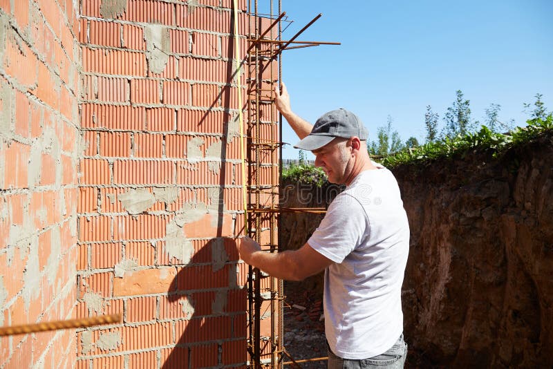 A construction worker is measuring a brick wall at a building site royalty free stock photos