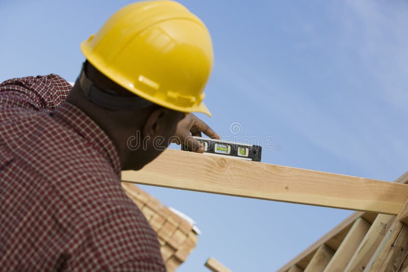 Rear view of a construction worker measuring with spirit level. Rear view of a construction worker measuring with spirit level