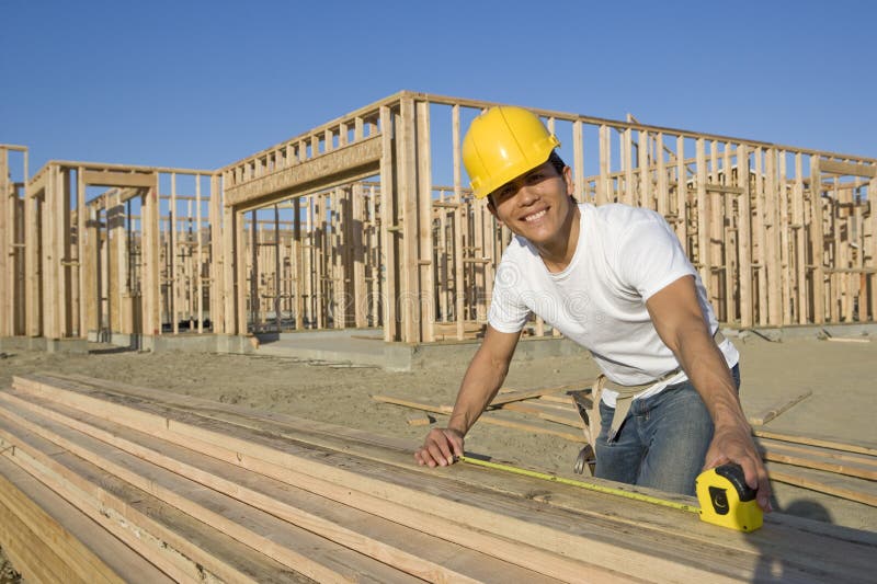 Construction Worker Measuring Planks stock photo