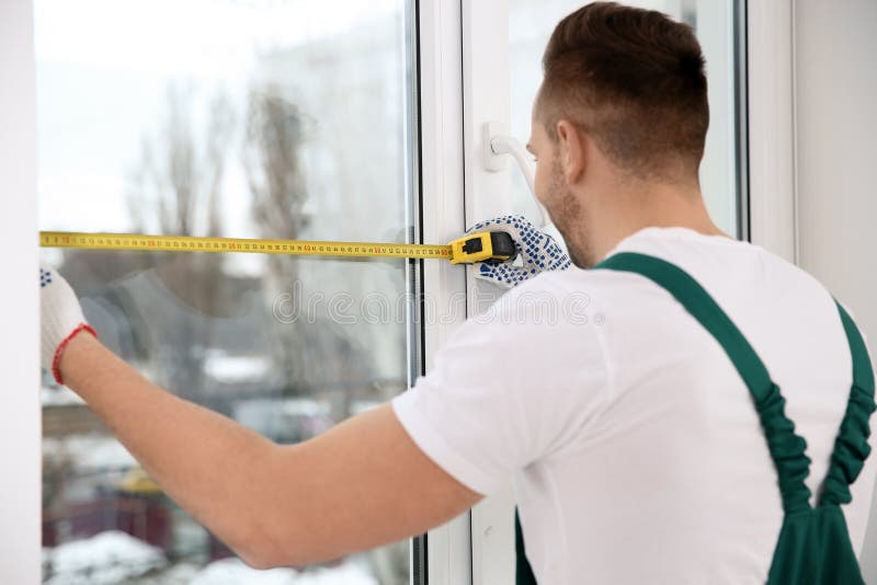 Construction worker measuring plastic window. Professional installation royalty free stock photos