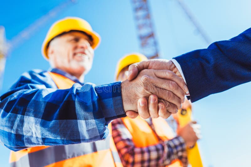 Construction Worker in Protective Uniform Shaking Hands with