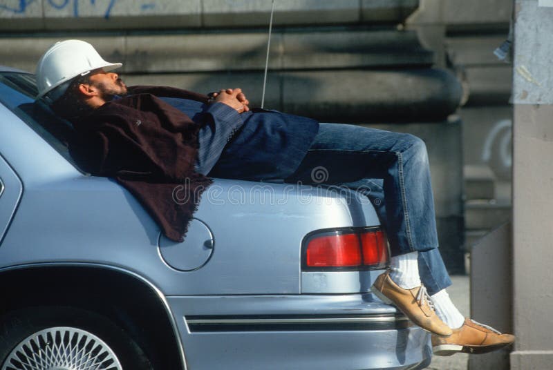 A construction worker resting on his car stock image