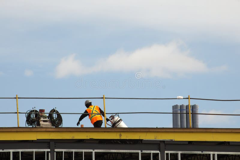 Construction Worker Roofer Carrying Propane Torch and Gas Tank To