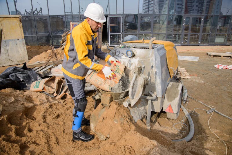 Construction Worker with Shovel and Bucket on Construction Site of New