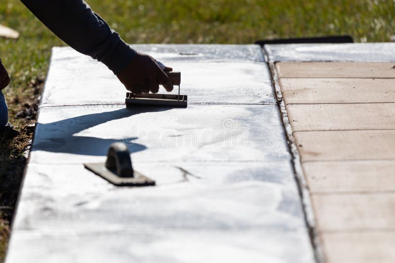 Construction Worker Smoothing Wet Cement with Hand Edger Tool Stock
