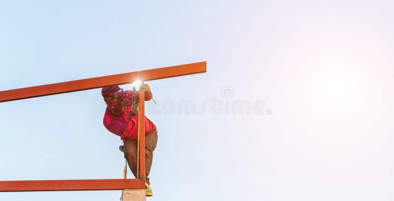 Construction worker welding steel for roof structure in process of house building