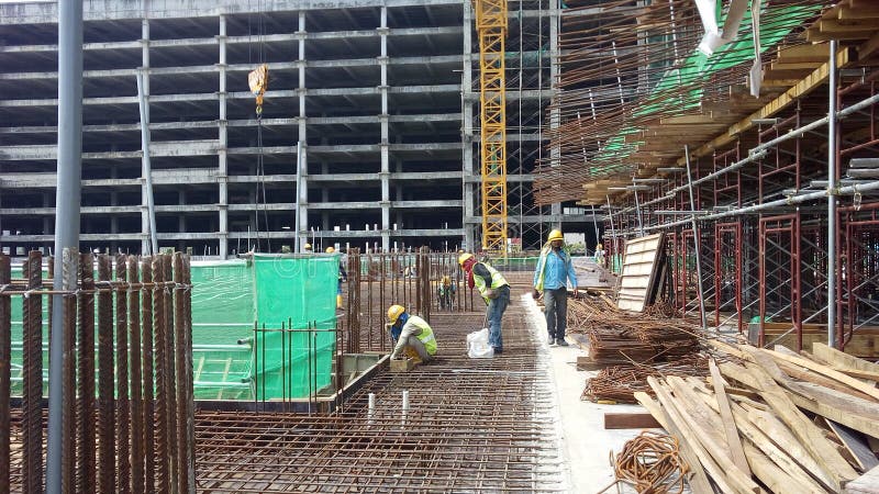 Construction workers fabricating steel reinforcement bar inside the timber formwork at the construction site.