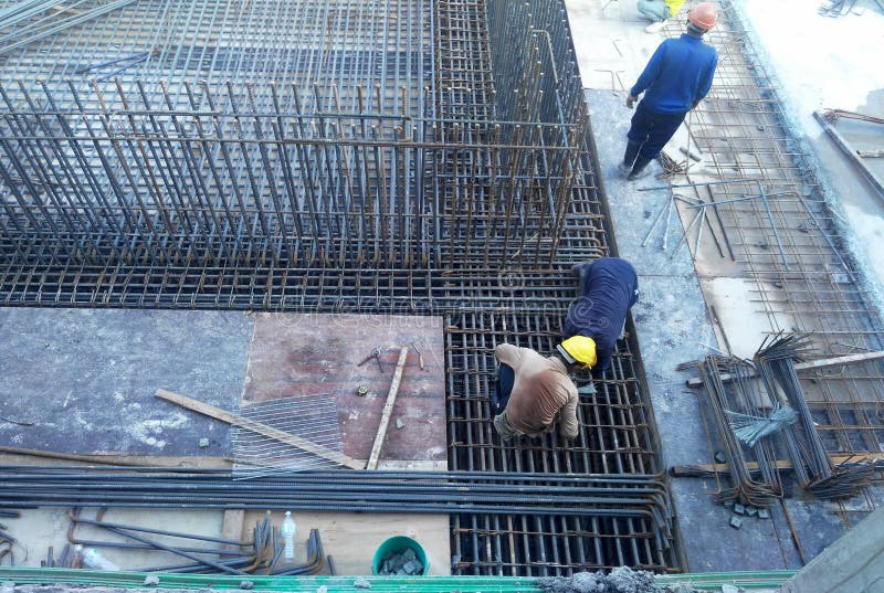 Construction workers fabricating steel reinforcement bar inside the timber formwork at the construction site.